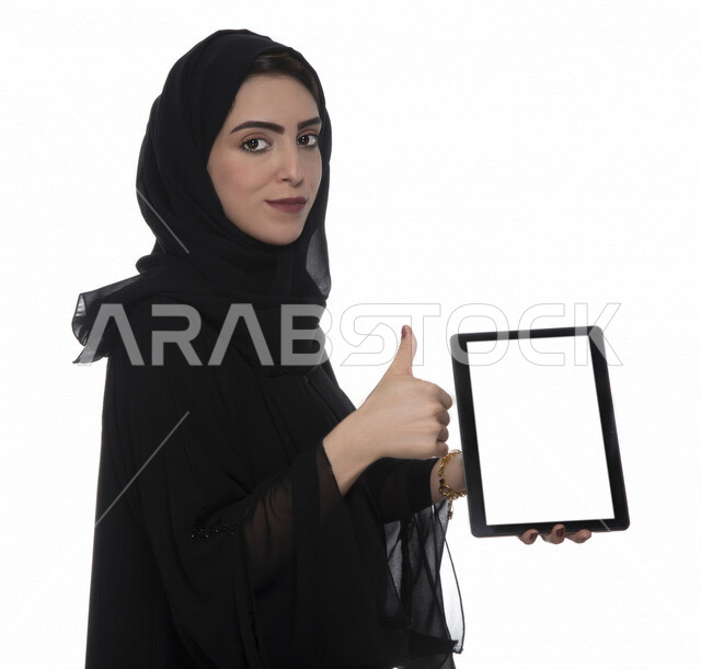 بورتريه لإمرأة عربيه خليجيه إماراتية بالزي التقليدي تستخدم جهاز لوحي بشاشة بيضاء مفرعة  ، التسويق الإلكتروني ، مفهوم التكنولوجيا وإستخدام الأجهزة التقنية الحديثة ، العمل عن بعد  , مكالمة فيديو , مشاهدة البرامج , خلفية بيضاء 