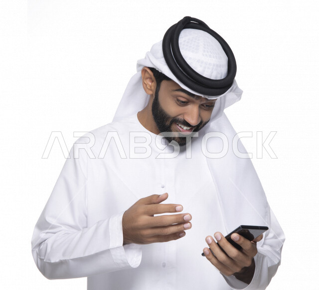 بورتريه لشاب عربي خليجي إماراتي يستعمل هاتف المحمول ، إيماءات وجه تدل على الفرح والسعادة , التواصل مع الأفراد ، طلبات أونلاين و تسويق ، علاقات اجتماعية  ، استخدام أجهزة تقنية ، خلفية بيضاء