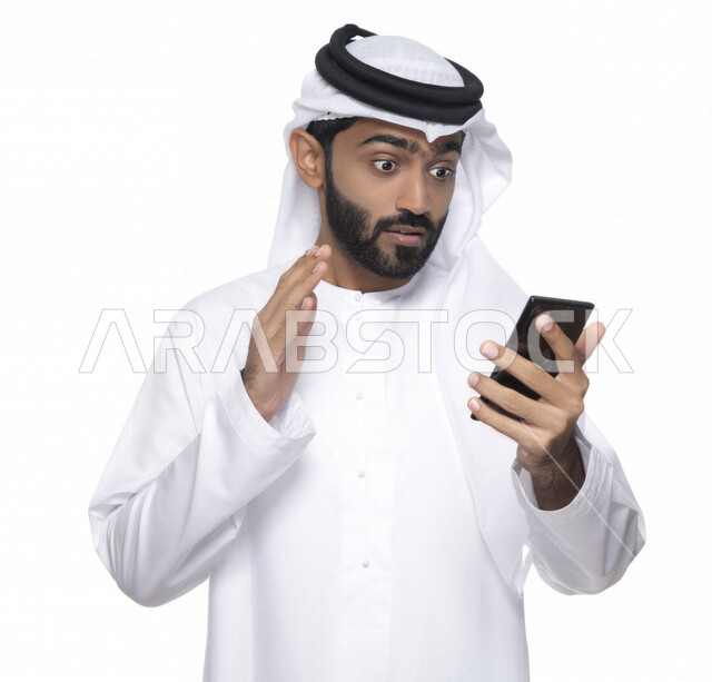 بورتريه لشاب عربي خليجي إماراتي يستعمل هاتف المحمول ، إيماءات وجه تدل على الاندهاش ,التواصل مع الأفراد ، طلبات أونلاين و تسويق ، علاقات اجتماعية  ، استخدام أجهزة تقنية ، خلفية بيضاء