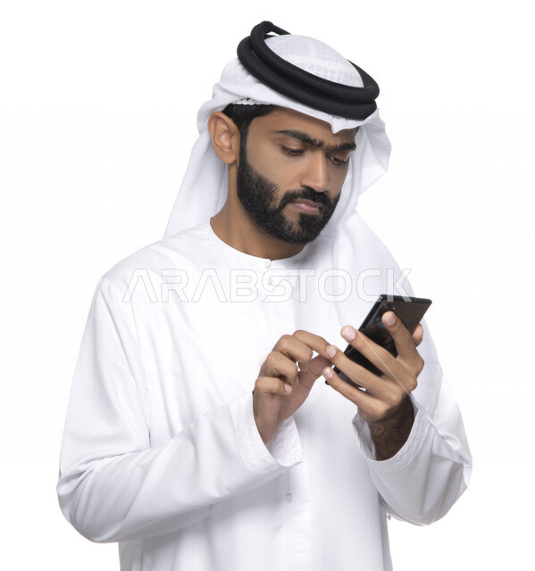 بورتريه لشاب عربي خليجي إماراتي يستعمل هاتف المحمول ، إيماءات وجه تدل على التركيز ,  التواصل مع الأفراد ، طلبات أونلاين و تسويق ، علاقات اجتماعية  ، استخدام أجهزة تقنية ، خلفية بيضاء