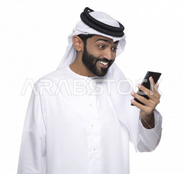 بورتريه لشاب عربي خليجي إماراتي يستعمل هاتف المحمول ، إيماءات وجه تدل على الفرح والسعادة , التواصل مع الأفراد ، طلبات أونلاين و تسويق ، علاقات اجتماعية  ، استخدام أجهزة تقنية ، خلفية بيضاء