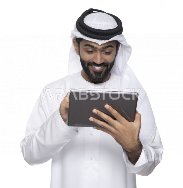 بورتريه لرجل عربي خليجي إماراتي بالزي التقليدي  يستخدم جهاز لوحي  ، التسويق الإلكتروني ، مفهوم التكنولوجيا وإستخدام الأجهزة التقنية الحديثة ، العمل عن بعد  , مكالمة فيديو , مشاهدة البرامج , خلفية بيضاء 