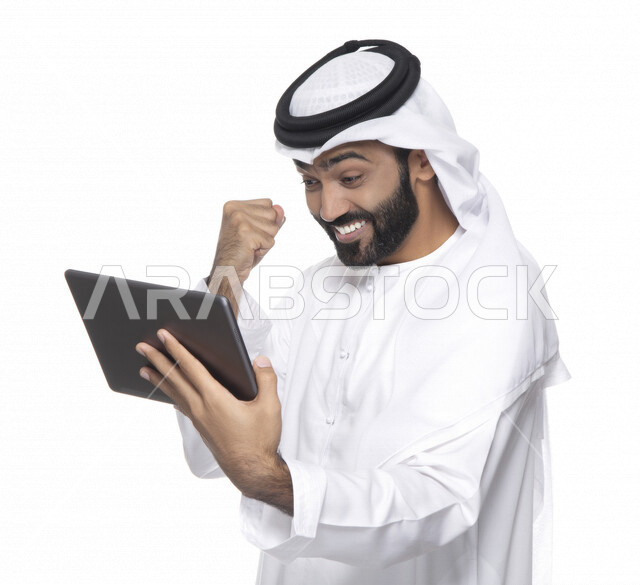 بورتريه لرجل عربي خليجي إماراتي بالزي التقليدي  يستخدم جهاز لوحي  ، التسويق الإلكتروني ، مفهوم التكنولوجيا وإستخدام الأجهزة التقنية الحديثة ، العمل عن بعد  , مكالمة فيديو , مشاهدة البرامج , خلفية بيضاء 