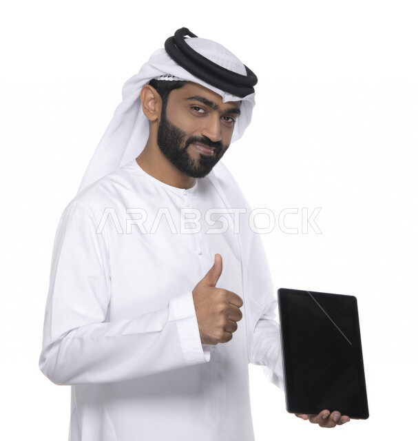 بورتريه لرجل عربي خليجي إماراتي بالزي التقليدي  يستخدم جهاز لوحي ويأشر بأصبع الإبهام للأعلى , ايماءات تدل على الإعجاب  ، التسويق الإلكتروني ، العمل عن بعد  , مكالمة فيديو , مشاهدة البرامج , خلفية بيضاء 