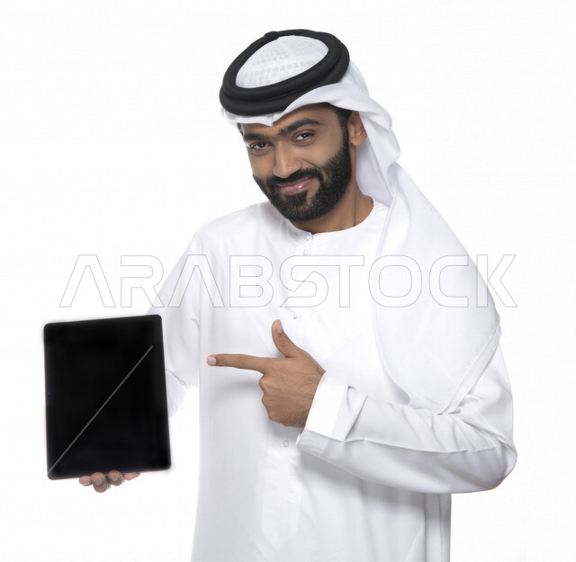 بورتريه لرجل عربي خليجي إماراتي بالزي التقليدي  يستخدم جهاز لوحي  ، التسويق الإلكتروني ، مفهوم التكنولوجيا وإستخدام الأجهزة التقنية الحديثة ، العمل عن بعد  , مكالمة فيديو , مشاهدة البرامج , خلفية بيضاء 