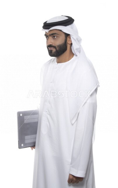 بورتريه لرجل أعمال عربي خليجي إماراتي يرتدي كندورة وغترة  ويحمل بيده جهاز الحاسوب , إيماءات وجه تدل على التركيز , خلفية بيضاء  