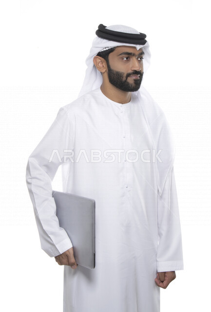 بورتريه لرجل أعمال عربي خليجي إماراتي يرتدي كندورة وغترة  ويحمل بيده جهاز الحاسوب , إيماءات وجه تدل على التركيز , خلفية بيضاء  