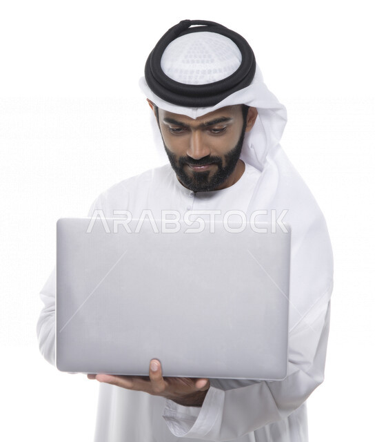 بورتريه لرجل أعمال عربي خليجي إماراتي يستخدم جهاز الحاسوب المحمول لإنجاز المهام، جلسة عمل، إنجاز المشاريع والمهام، مهن وأعمال تجارية، متابعة ومناقشة العمل، عقد إجتماع عمل عبر الإنترنت، التسويق الإلكتروني، خلفية بيضاء 