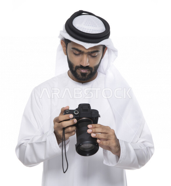 بورتريه لشاب عربي خليجي إماراتي ، يحمل بيده كاميرا التصوير ، يلتقط الصور باستخدام كاميرا التصوير ، التصوير الفوتوغرافي ، موهبة واحتراف فن التصوير ، مصور إماراتي  ، كاميرا عالية الدقة ، خلفية بيضاء 