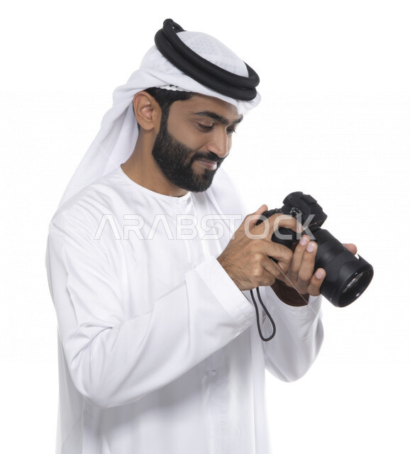 بورتريه لشاب عربي خليجي إماراتي ، يحمل بيده كاميرا التصوير ، يلتقط الصور باستخدام كاميرا التصوير ، التصوير الفوتوغرافي ، موهبة واحتراف فن التصوير ، مصور إماراتي  ، كاميرا عالية الدقة ، خلفية بيضاء 
