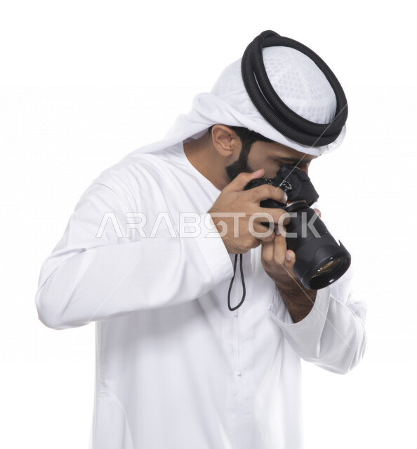 بورتريه لشاب عربي خليجي إماراتي ، يحمل بيده كاميرا التصوير ، يلتقط الصور باستخدام كاميرا التصوير ، التصوير الفوتوغرافي ، موهبة واحتراف فن التصوير ، مصور إماراتي  ، كاميرا عالية الدقة ، خلفية بيضاء 