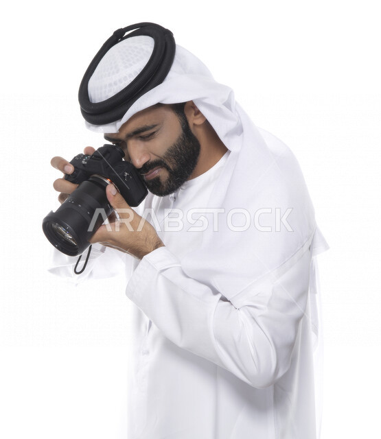 بورتريه لشاب عربي خليجي إماراتي ، يحمل بيده كاميرا التصوير ، يلتقط الصور باستخدام كاميرا التصوير ، التصوير الفوتوغرافي ، موهبة واحتراف فن التصوير ، مصور إماراتي  ، كاميرا عالية الدقة ، خلفية بيضاء 