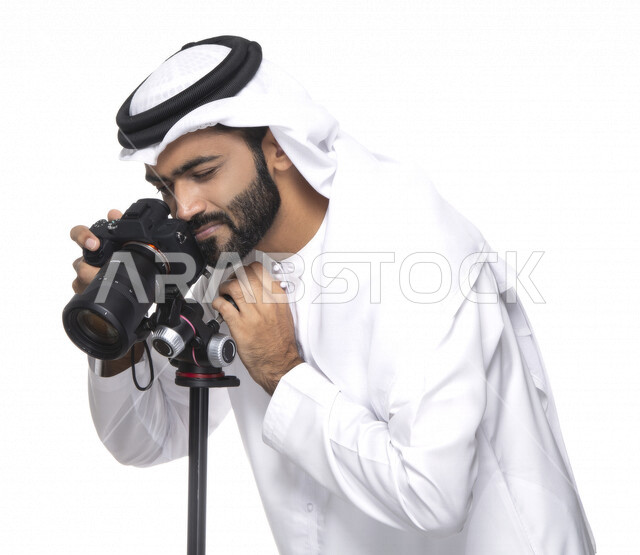 بورتريه لشاب عربي خليجي إماراتي ، يحمل بيده كاميرا التصوير ، يلتقط الصور باستخدام كاميرا التصوير ، التصوير الفوتوغرافي ، موهبة واحتراف فن التصوير ، مصور إماراتي  ، كاميرا عالية الدقة ، خلفية بيضاء 