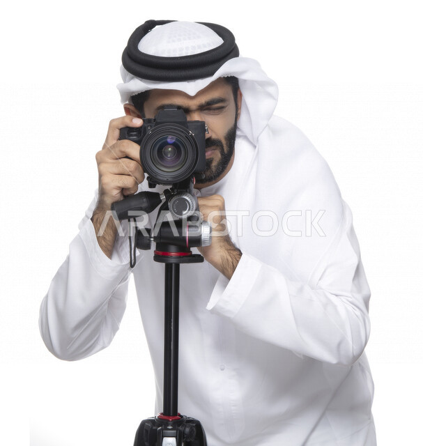 بورتريه لشاب عربي خليجي إماراتي ، يحمل بيده كاميرا التصوير ، يلتقط الصور باستخدام كاميرا التصوير ، التصوير الفوتوغرافي ، موهبة واحتراف فن التصوير ، مصور إماراتي  ، كاميرا عالية الدقة ، خلفية بيضاء 