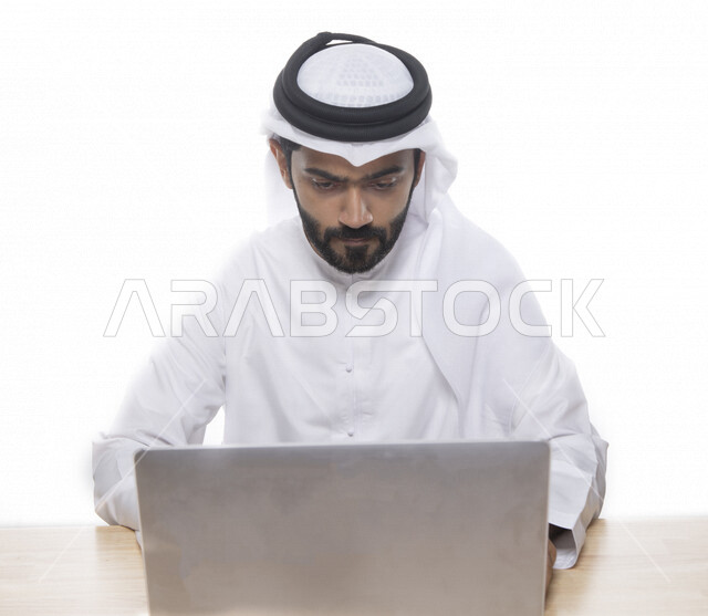 بورتريه لرجل أعمال عربي خليجي إماراتي يستخدم جهاز الحاسوب المحمول لإنجاز المهام، جلسة عمل، إنجاز المشاريع والمهام، مهن وأعمال تجارية، متابعة ومناقشة العمل، عقد إجتماع عمل عبر الإنترنت، التسويق الإلكتروني، خلفية بيضاء 