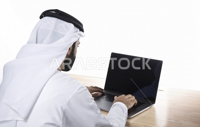بورتريه لرجل أعمال عربي خليجي إماراتي ، إستخدام جهاز الحاسوب المحمول بشاشة سوداء مفرغة ، إنجاز مهام العمل، تصفح الإنترنت، جلسة عمل، عقد إجتماع عمل عبر الإنترنت، التسويق الإلكتروني، خلفية بيضاء 