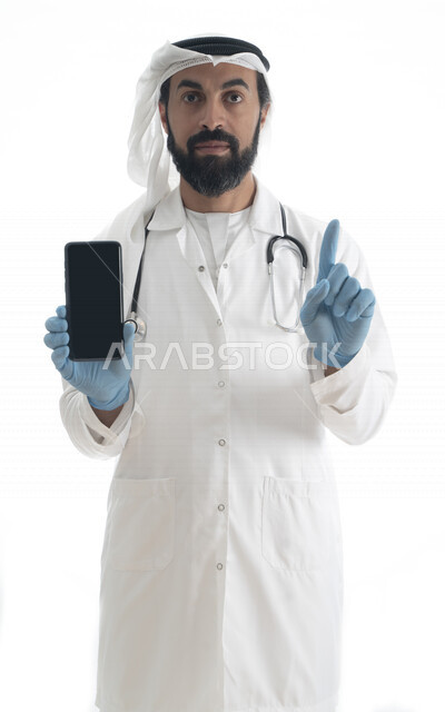 بورتريه لطبيب عربي خليجي إماراتي بزي التقليدي ,  يرتدي معطف طبي وسماعة طبية , يضع القفازات  لإتباع اساسيات السلامة و خدماته للمرضى بكل كفاءه ، هاتف محمول بشاشة سوداء مفرغة ,خلفية بيضاء