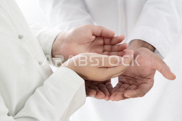 Portrait, close-up of Emirati, Arab, Gulf hands, father and son, Islamic giving of goodness, supplication, diligence in worship, white background