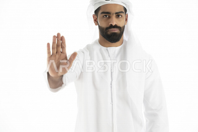 Portrait of an Arab Emirati Gulf man wearing Emirati dress, gestures indicating the order to stop doing something, feeling fear and annoyance, rejection and abstinence, white background