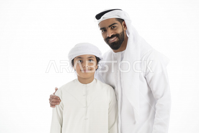 بورتريه لرجل عربي إماراتي خليجي يرتدي الزي التقليدي بجانب طفله , إماراتي يحضن ولده بكل حب وحنان    ، تجمع عائلي ، تعابير وجه مبتسمة  ، قضاء أوقات عائلية جميلة  ، خلفية بيضاء