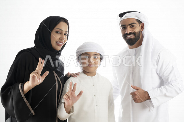 بورتريه لزوجان عربيان خليجيان إماراتيان بجانب إبنهم يرتديان  الزي الإماراتي التقليدي , قضاء وقت ممتع مع العائلة , إيماءات وجه تدل على السعادة والفرح , خلفية بيضاء 