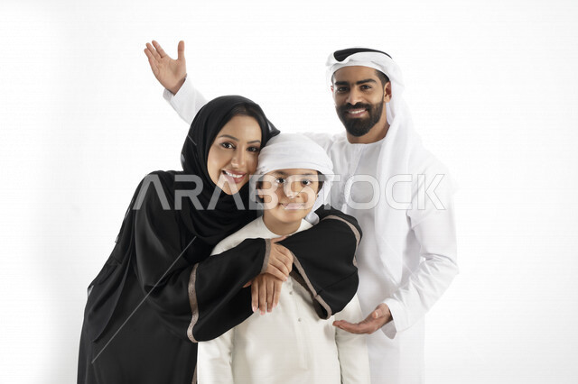 بورتريه لزوجان عربيان خليجيان إماراتيان بجانب إبنهم يرتديان  الزي الإماراتي التقليدي , قضاء وقت ممتع مع العائلة , إيماءات وجه تدل على السعادة والفرح , خلفية بيضاء 
