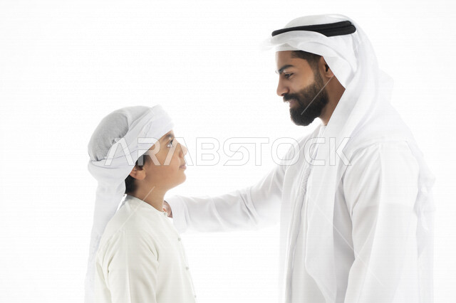 بورتريه لرجل عربي إماراتي خليجي مع ابنه بايماءات وجه و يدين مختلفة ، تجمع عائلي ، تعابير وجه ، قضاء أوقات عائلية ، خلفية بيضاء
