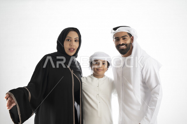 بورتريه لزوجان عربيان خليجيان إماراتيان بجانب إبنهم يرتديان  الزي الإماراتي التقليدي , قضاء وقت ممتع مع العائلة , إيماءات وجه تدل على الاندهاش ,  خلفية بيضاء 