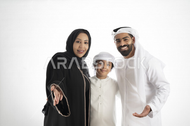 بورتريه لزوجان عربيان خليجيان إماراتيان بجانب إبنهم يرتديان  الزي الإماراتي التقليدي , قضاء وقت ممتع مع العائلة , إيماءات وجه تدل على الاندهاش ,  خلفية بيضاء 