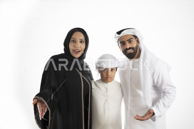بورتريه لزوجان عربيان خليجيان إماراتيان بجانب إبنهم يرتديان  الزي الإماراتي التقليدي , قضاء وقت ممتع مع العائلة , إيماءات وجه تدل على الاندهاش ,  خلفية بيضاء 