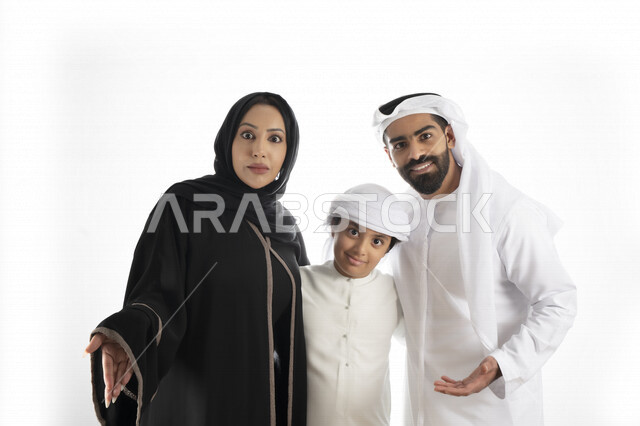 بورتريه لزوجان عربيان خليجيان إماراتيان بجانب إبنهم يرتديان  الزي الإماراتي التقليدي , قضاء وقت ممتع مع العائلة , إيماءات وجه تدل على الاندهاش ,  خلفية بيضاء 