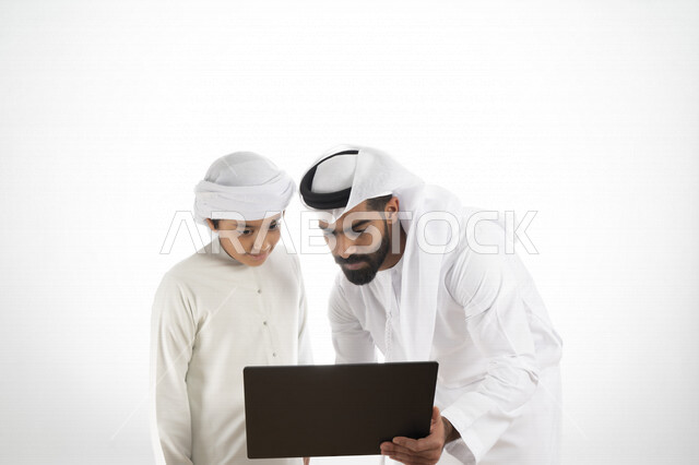 بورتريه لأب عربي خليجي إماراتي يرتدي الزي التقليدي الإماراتي كندورة وغترة  ، تعليم الطفل كيفية استخدام الكمبيوتر في المدرسة، استخدام لوحة المفاتيح للكتابة، التعليم الالكتروني، التعليم الفعال، خلفية بيضاء 