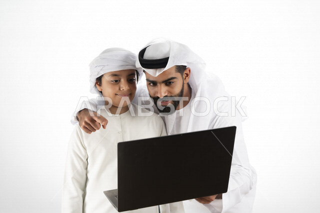Portrait of an Emirati Arab Gulf father wearing the Emirati traditional costume as a skirt and a ghutra, teaching a child how to use a computer at school, using the keyboard for writing, e-learning, effective education, white background