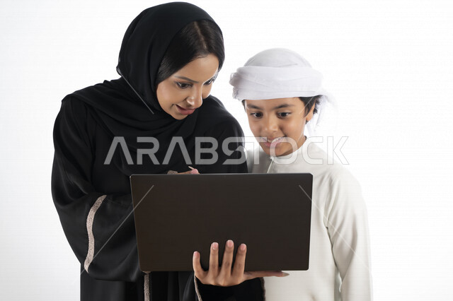 بورتريه لأم عربية خليجية إماراتية ترتدي الزي التقليدي الإماراتي شيلة وعباية ، تعليم الطفل كيفية استخدام الكمبيوتر في المدرسة، استخدام لوحة المفاتيح للكتابة، التعليم الالكتروني، التعليم الفعال، خلفية بيضاء 