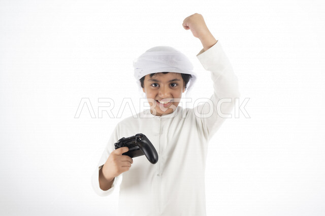 Portrait of an Arab Emirati Gulf child with a joystick in his hand and playing video games, facial gestures indicating integration and interaction with the game, fun and entertainment with video games, entertainment PlayStation games, white background