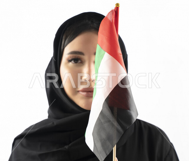 بورتريه لمرأة عربية خليجية إماراتية، مبتسمة تنظر إلى الكاميرا، تحمل علم الإمارات العربية المتحدة، الإحتفال باليوم الوطني الإماراتي، هوية اليوم الوطني الإماراتي 51 ، يوم استقلال الإمارات، حب الوطن، العيد الوطني الإماراتي