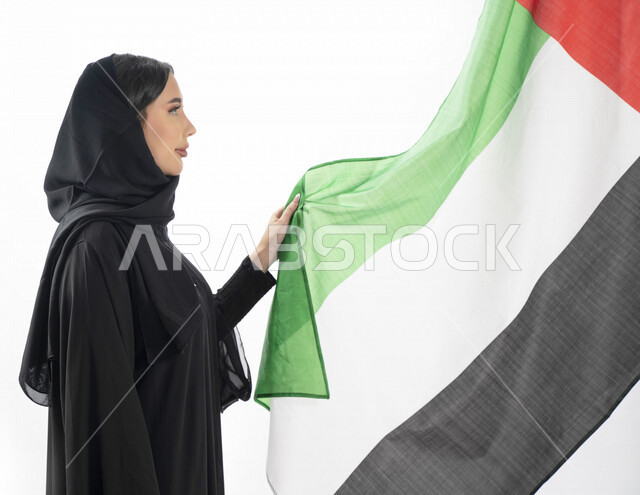 بورتريه بزاوية من الجنب لمرأة عربية خليجية إماراتية، تقف بجانب علم دولة الإمارات العربية المتحدة ، الإحتفال باليوم الوطني الإماراتي، هوية اليوم الوطني الإماراتي 51 ، يوم استقلال الإمارات، حب الوطن، العيد الوطني الإماراتي، الفخر والإعتزاز، خلفية بيضاء