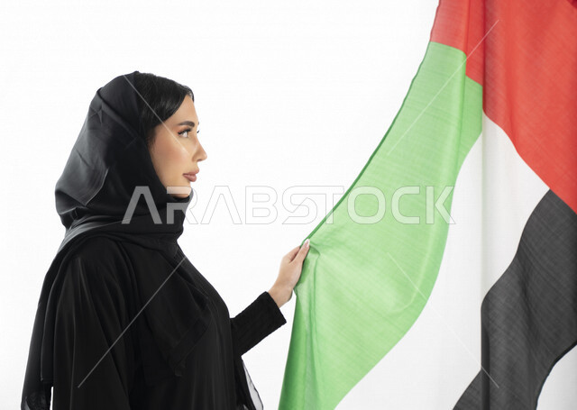 بورتريه بزاوية من الجنب لمرأة عربية خليجية إماراتية، تقف بجانب علم دولة الإمارات العربية المتحدة ، الإحتفال باليوم الوطني الإماراتي، هوية اليوم الوطني الإماراتي 51 ، يوم استقلال الإمارات، حب الوطن، العيد الوطني الإماراتي، الفخر والإعتزاز، خلفية بيضاء