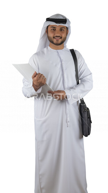 بورتريه طالب جامعي عربي خليجي اماراتي يضع الحقيبة على ظهرة ، يحمل بيده كتاب جامعي، قراءة الكتب الجامعية، مراجعة الدروس اليومية، التعليم الجامعي في الإمارات العربية المتحدة ، خلفية بيضاء .