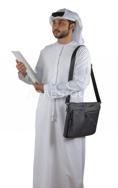 بورتريه طالب جامعي عربي خليجي اماراتي يضع الحقيبة على ظهرة ، يحمل بيده كتاب جامعي، قراءة الكتب الجامعية، مراجعة الدروس اليومية، التعليم الجامعي في الإمارات العربية المتحدة ، خلفية بيضاء .