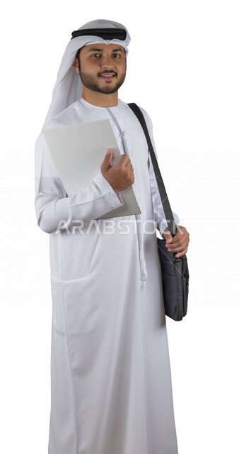 بورتريه طالب جامعي عربي خليجي اماراتي يضع الحقيبة على ظهرة ، يحمل بيده كتاب جامعي، قراءة الكتب الجامعية، مراجعة الدروس اليومية، التعليم الجامعي في الإمارات العربية المتحدة ، خلفية بيضاء .