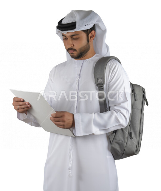 بورتريه طالب جامعي عربي خليجي اماراتي يضع الحقيبة على ظهرة ، يحمل بيده كتاب جامعي، قراءة الكتب الجامعية، مراجعة الدروس اليومية، التعليم الجامعي في الإمارات العربية المتحدة ، خلفية بيضاء .