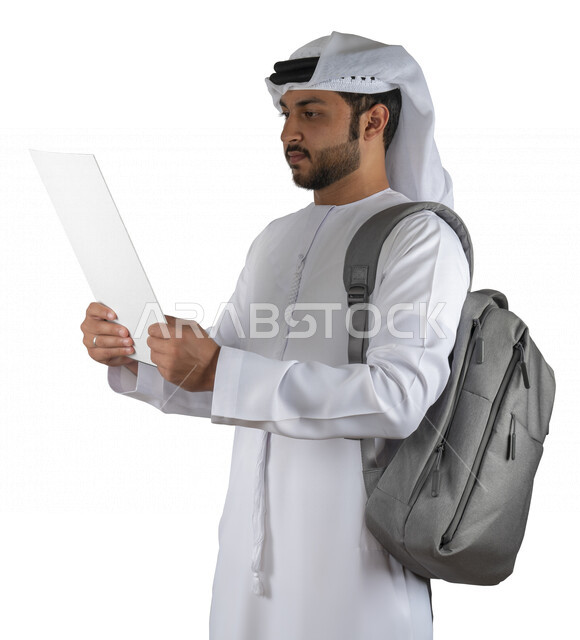 بورتريه طالب جامعي عربي خليجي اماراتي يضع الحقيبة على ظهرة ، يحمل بيده كتاب جامعي، قراءة الكتب الجامعية، مراجعة الدروس اليومية، التعليم الجامعي في الإمارات العربية المتحدة ، خلفية بيضاء .