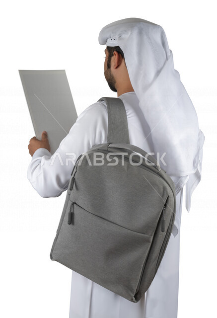 بورتريه طالب جامعي عربي خليجي اماراتي يضع الحقيبة على ظهرة ، يحمل بيده كتاب جامعي، قراءة الكتب الجامعية، مراجعة الدروس اليومية، التعليم الجامعي في الإمارات العربية المتحدة ، خلفية بيضاء .