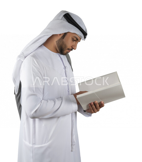 Portrait of an Arab Gulf Emirati university student with a bag on his back, holding a university book in his hand, reading university books, reviewing daily lessons, university education in the United Arab Emirates, white background.