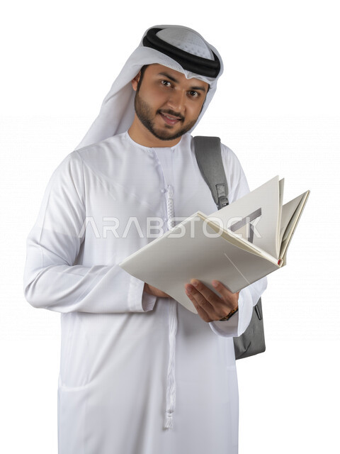 بورتريه طالب جامعي عربي خليجي اماراتي يضع الحقيبة على ظهرة ، يحمل بيده كتاب جامعي، قراءة الكتب الجامعية، مراجعة الدروس اليومية، التعليم الجامعي في الإمارات العربية المتحدة ، خلفية بيضاء .
