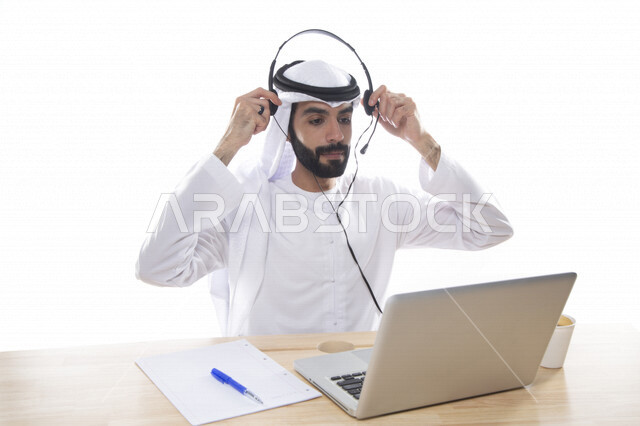 بورتريه موظف عربي خليجي اماراتي يعمل في خدمة العملاء ويرتدي سماعة الاتصال، استعلامات واستفسارات، الاجابه على اسئلة العملاء، اجراء اتصال فيديو من خلال الحاسوب ، متابعة وتطوير العمل , خلفية بيضاء .