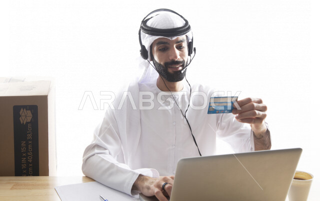 بورتريه موظف عربي خليجي اماراتي يعمل في خدمة العملاء ويرتدي سماعة الاتصال، استعلامات واستفسارات، الاجابه على اسئلة العملاء، اجراء اتصال فيديو من خلال الحاسوب ، متابعة وتطوير العمل , خلفية بيضاء .