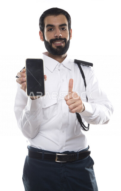 بورتريه رجل أمن عربي خليجي إماراتي يرتدي الزي الرسمي للعمل , يحمل بيده الهاتف المحمول , إشارات يد تؤشر للتقنية , مهن و وظائف , استخدام التقنية الحديثة للحفاظ على الأمن والسلامة , خلفية بيضاء .