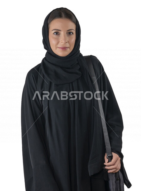 بورتريه لطالبة جامعية عربية إماراتيه خليجية محجبة مبتسمه تحمل حقيبة اللابتوب على كتفها, تنظر الى الكاميرا, موظفه في شركه إماراتيه, شابة متشوقة للذهاب الى العمل, خلفية بيضاء